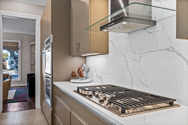 kitchen with wall chimney range hood, appliances with stainless steel finishes, decorative backsplash, and light tile patterned floors