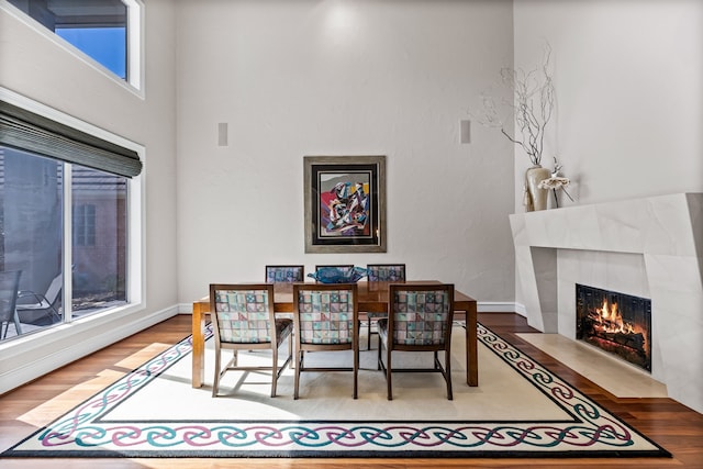 dining space with a tiled fireplace, baseboards, and wood finished floors