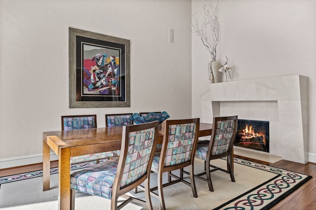5819 Coolwater Cv, Dallas, TX 75252 - dining room featuring wood finished floors, a tile fireplace, a textured wall, and baseboards