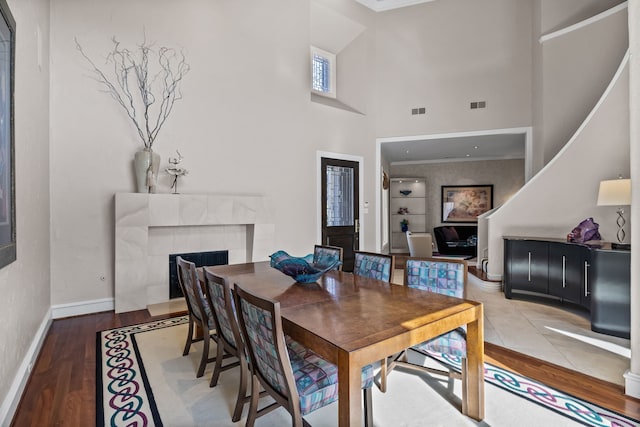 5819 Coolwater Cv, Dallas, TX 75252 - dining space with a tile fireplace, a towering ceiling, ornamental molding, baseboards, and wood finished floors