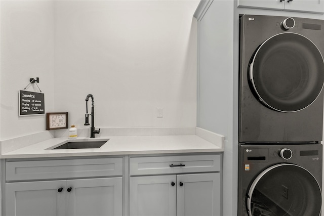 washroom featuring cabinet space, stacked washer / drying machine, and a sink
