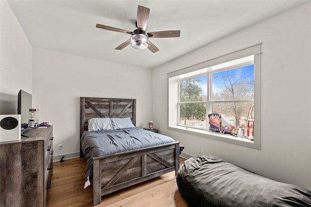 bedroom featuring light wood-style flooring, a ceiling fan, and baseboards