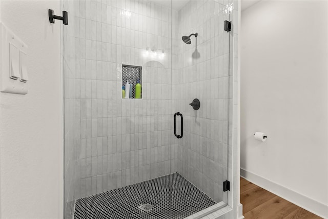 full bathroom featuring a shower stall, wood finished floors, and baseboards