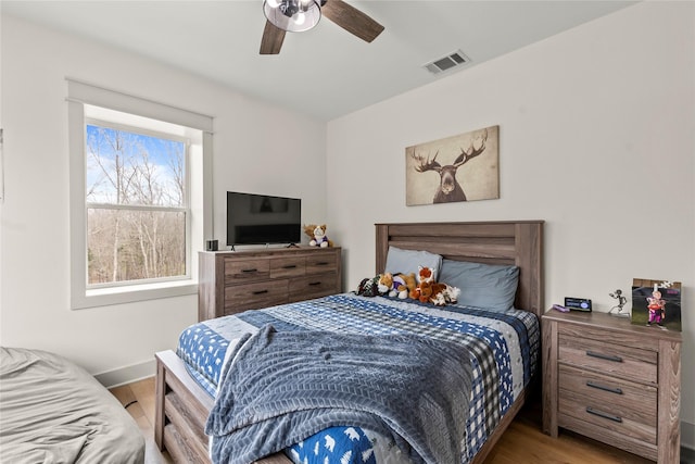 bedroom featuring visible vents, baseboards, wood finished floors, and a ceiling fan