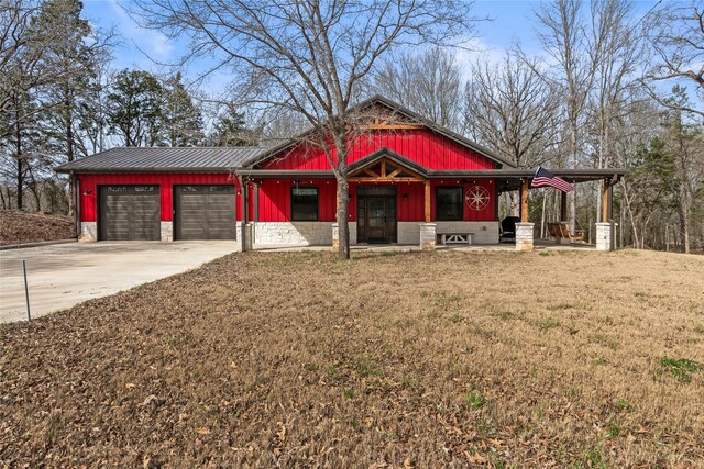 view of front of home featuring concrete driveway, an attached garage, a front yard, and metal roof