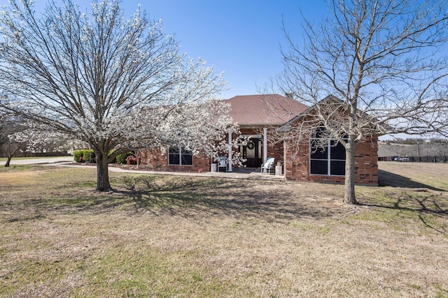 back of property with brick siding, a yard, and roof with shingles