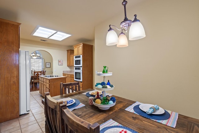 dining area with light tile patterned flooring, visible vents, arched walkways, and a chandelier