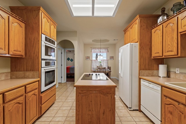 kitchen with light tile patterned floors, white appliances, a kitchen island, and light countertops