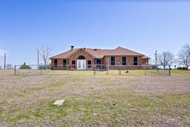 view of front of house with brick siding, a chimney, a front yard, and fence