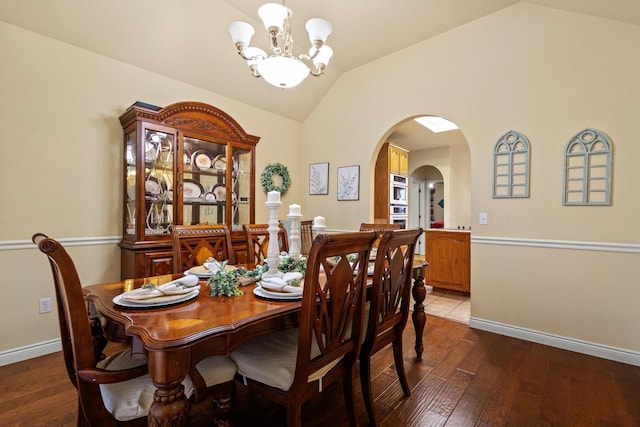 dining room with baseboards, vaulted ceiling, an inviting chandelier, wood finished floors, and arched walkways