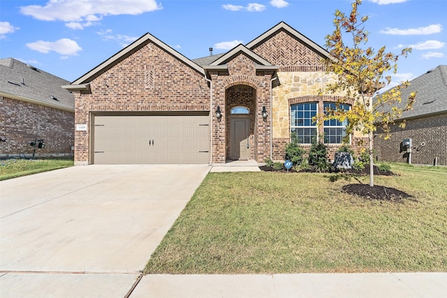 french country style house with a front lawn, an attached garage, brick siding, and driveway