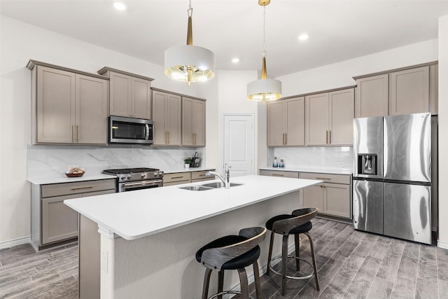 kitchen with gray cabinets, appliances with stainless steel finishes, wood finish floors, and a sink