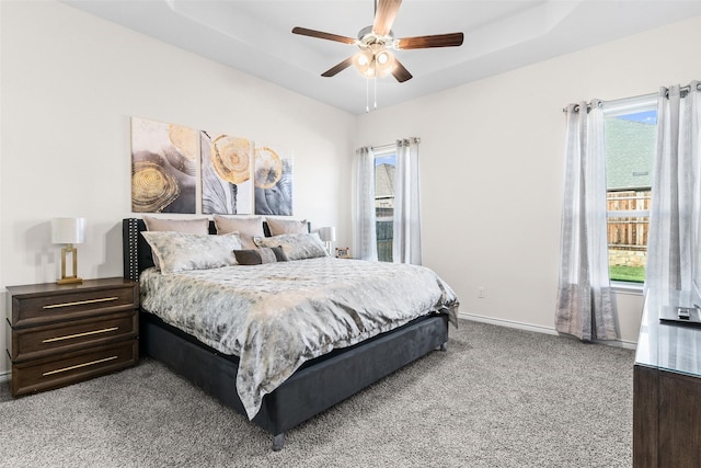 bedroom with a tray ceiling, baseboards, carpet floors, and ceiling fan