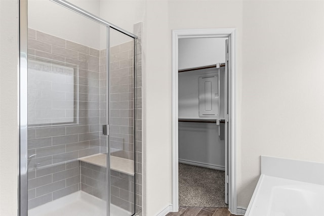 bathroom featuring a bath, a stall shower, a walk in closet, and baseboards