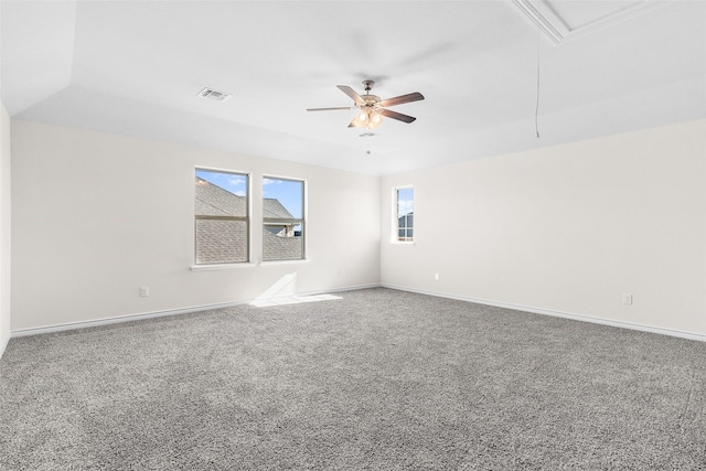 carpeted empty room with attic access, a ceiling fan, visible vents, and baseboards