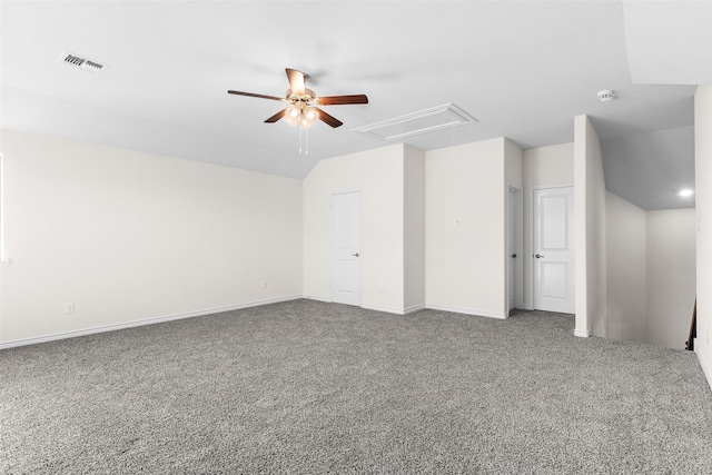 spare room featuring a ceiling fan, visible vents, carpet floors, attic access, and vaulted ceiling