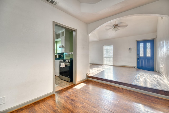 foyer entrance with a ceiling fan, visible vents, baseboards, arched walkways, and hardwood / wood-style flooring