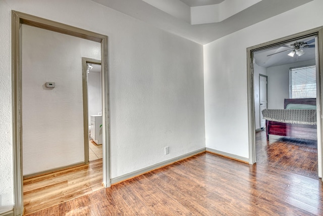 unfurnished room with wood finished floors, baseboards, and ceiling fan
