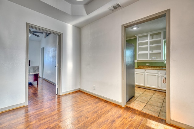 spare room featuring visible vents, baseboards, light wood-style floors, and ceiling fan