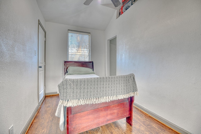 bedroom featuring a textured wall, a ceiling fan, baseboards, and wood finished floors