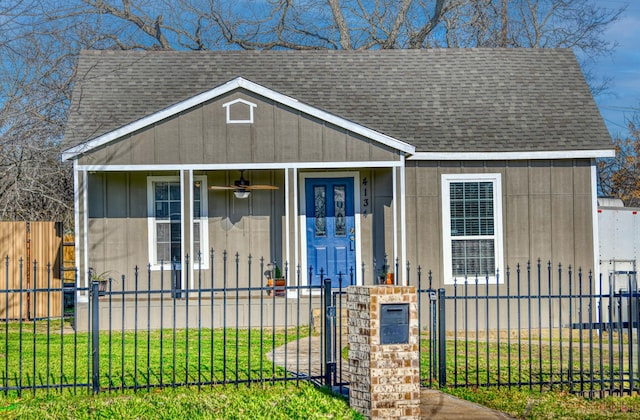 view of front facade with a fenced front yard, covered porch, and a shingled roof