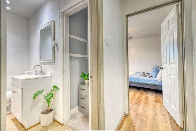corridor with a sink, light wood-style flooring, and a textured wall