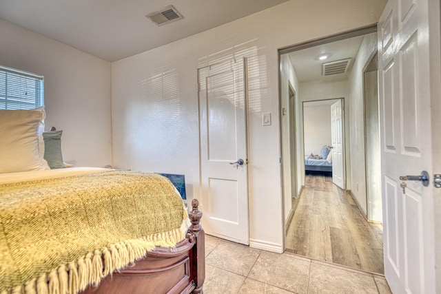 bedroom featuring light tile patterned floors, visible vents, and baseboards