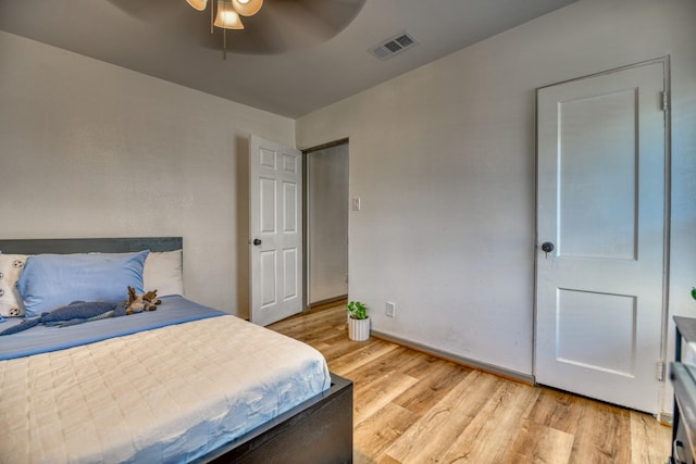bedroom featuring a ceiling fan, light wood-style flooring, baseboards, and visible vents