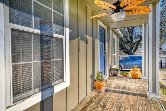 exterior space featuring fence, board and batten siding, a ceiling fan, and a sunroom