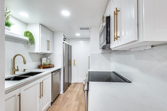 kitchen with open shelves, light wood-style floors, white cabinets, a sink, and stainless steel appliances