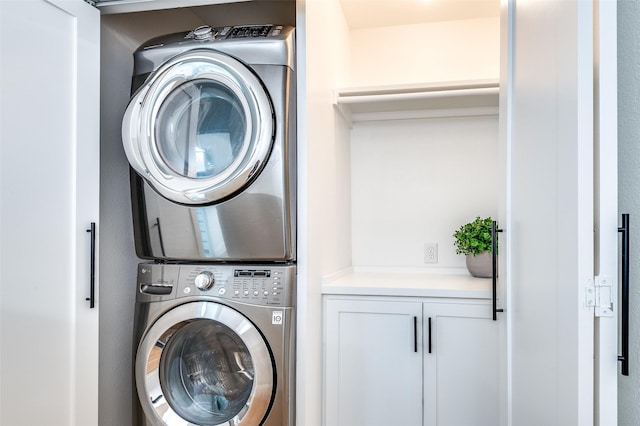laundry room featuring cabinet space and stacked washer / dryer