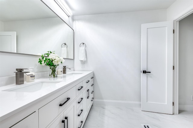 full bath with double vanity, a sink, marble finish floor, and baseboards