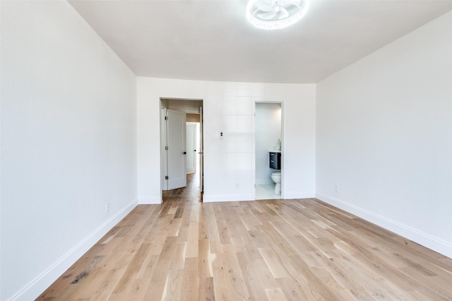 unfurnished bedroom with baseboards, ensuite bath, and light wood-type flooring