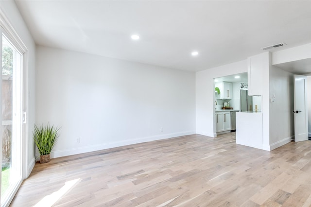unfurnished living room featuring visible vents, light wood-style floors, baseboards, recessed lighting, and a sink
