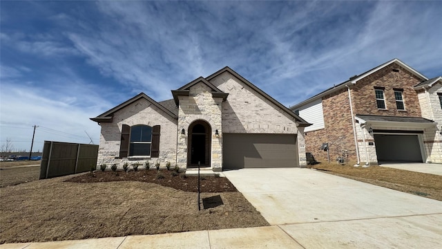 french provincial home with stone siding, brick siding, a garage, and driveway