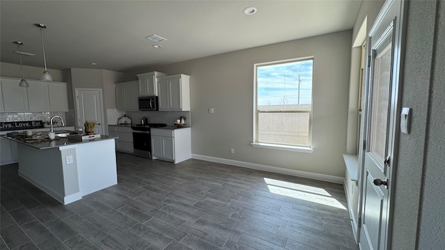 kitchen featuring visible vents, a sink, dark countertops, stainless steel appliances, and decorative backsplash