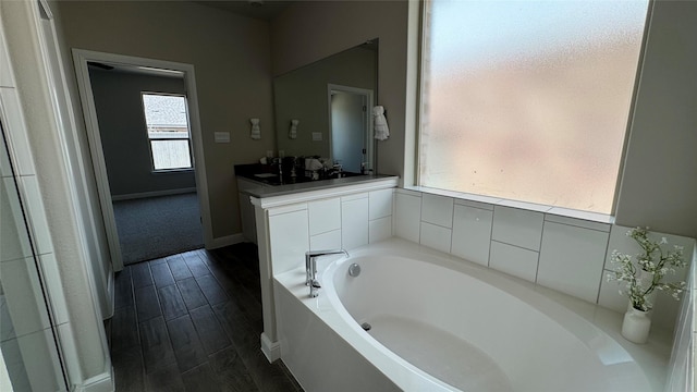 full bath with a bath, baseboards, and wood finish floors