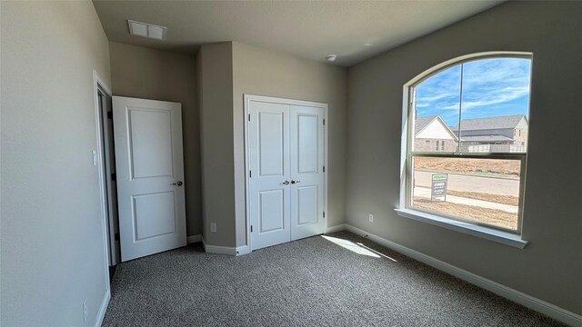 unfurnished bedroom with carpet, visible vents, a closet, and baseboards