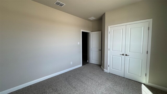 unfurnished bedroom with carpet, visible vents, a closet, and baseboards