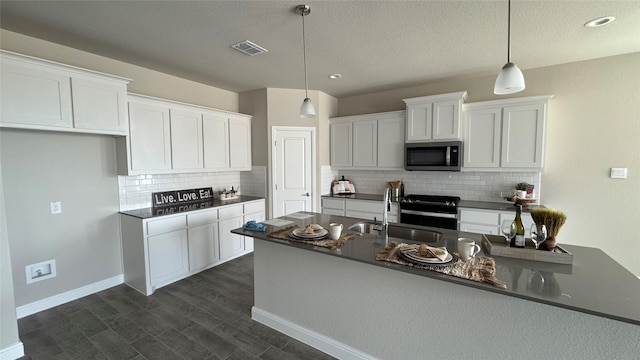 kitchen featuring a sink, stainless steel appliances, dark countertops, and white cabinets