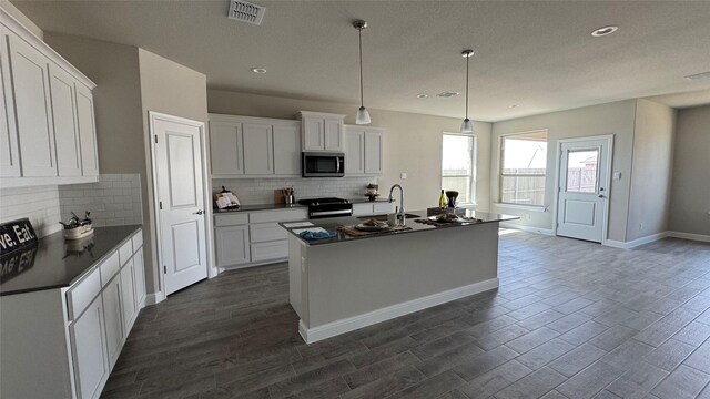 kitchen with visible vents, dark countertops, stainless steel appliances, white cabinets, and dark wood-style flooring