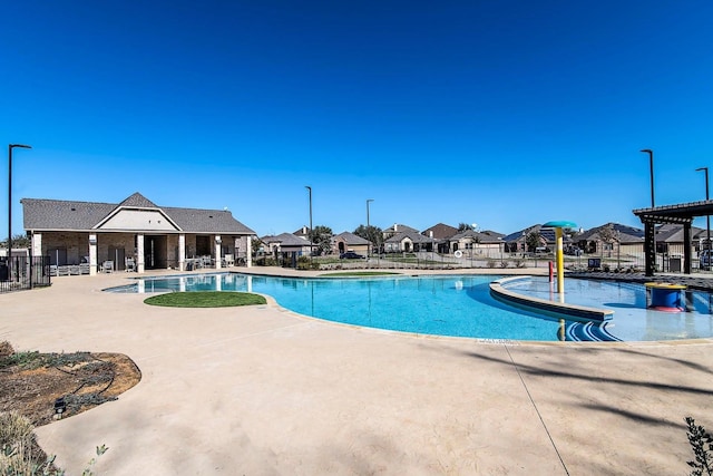 community pool featuring a patio area, a residential view, and fence