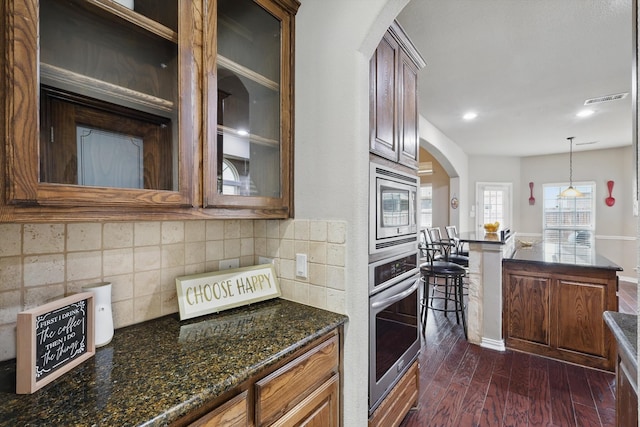 9645 Salvia Dr, Fort Worth, TX 76177 - kitchen featuring stainless steel appliances, arched walkways, dark wood finished floors, tasteful backsplash, and glass insert cabinets