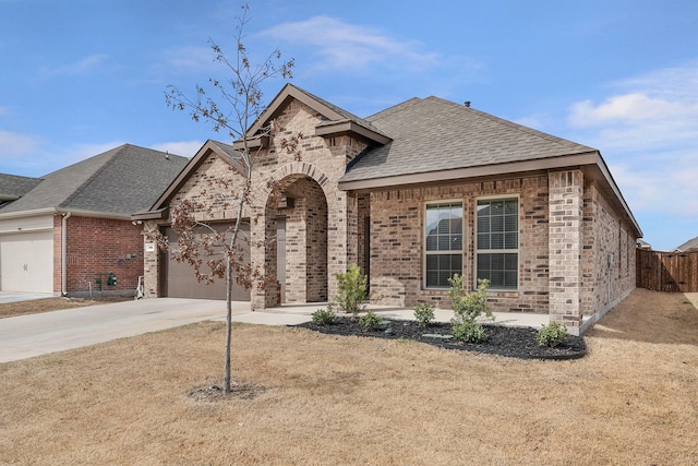 view of front of home featuring a garage, brick siding, driveway, and a shingled roof