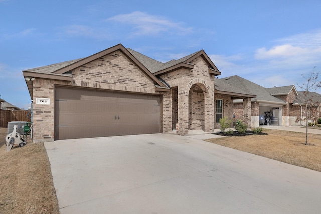 french provincial home featuring brick siding, roof with shingles, concrete driveway, and an attached garage