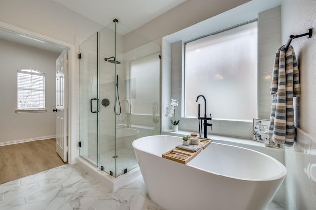 full bathroom featuring a shower stall, a freestanding tub, and marble finish floor