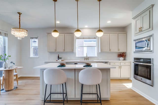 kitchen with light countertops, a kitchen island, light wood-style floors, a kitchen bar, and stainless steel appliances