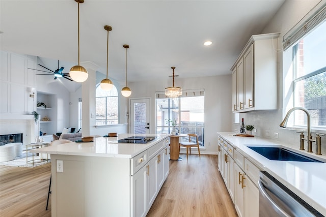 kitchen featuring black electric stovetop, light wood-style flooring, a healthy amount of sunlight, stainless steel dishwasher, and a sink