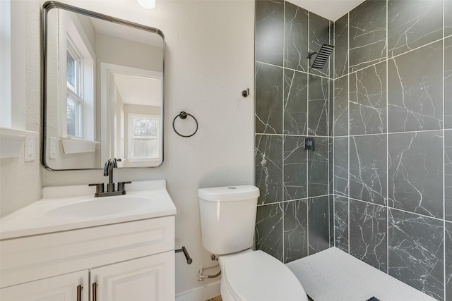 full bath featuring tiled shower, toilet, and vanity