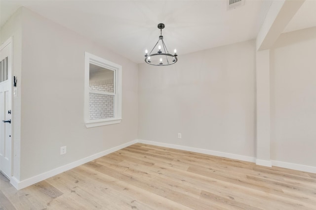 unfurnished room with visible vents, baseboards, light wood-type flooring, and an inviting chandelier